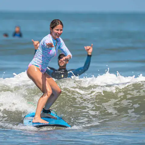 Une élève debout sur sa planche dans les vagues