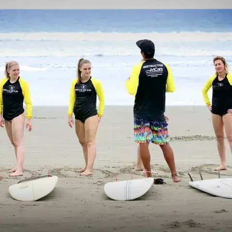 Groupe d'élèves et planches sur la plage avant un cours