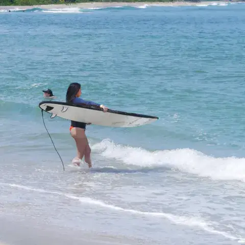 Une surfeuse sort de l'eau avec sa planche
