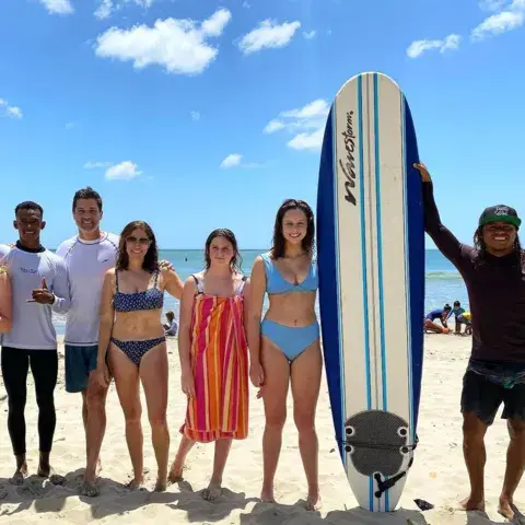 Groupe sur la plage autour d'une planche de surf