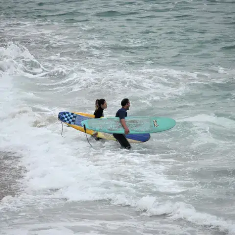 Deux surfeurs entrant dans l'eau avec leurs planches