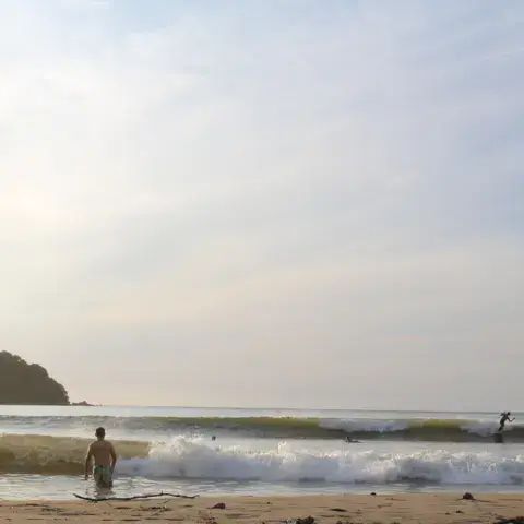 Surfeur entrant dans l'eau sur la plage