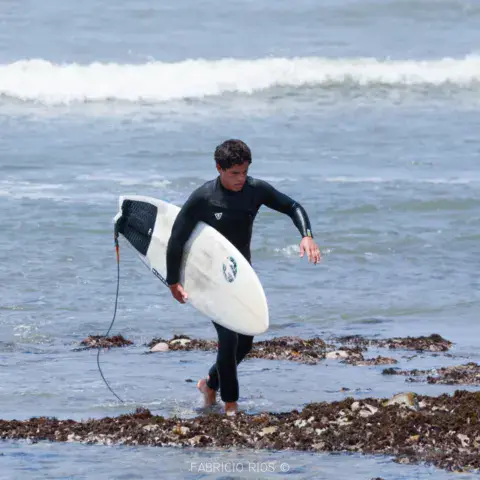 Surfeur sortant de l'eau avec sa planche