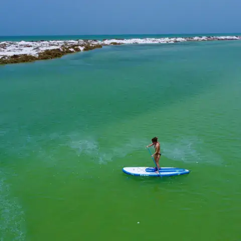 Pratiquant de stand up paddle sur une eau turquoise