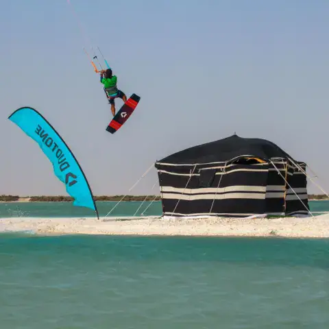 Saut en kitesurf devant une tente de camp