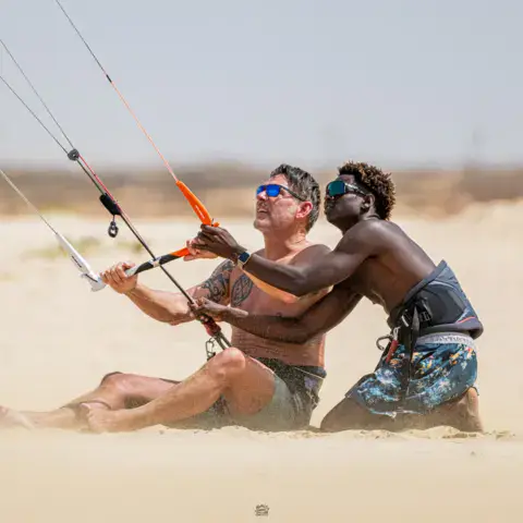 Un moniteur explique le pilotage de l'aile sur le sable