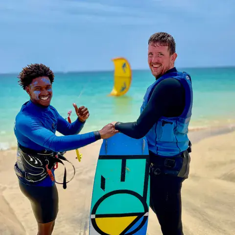 Moniteur et élève sur la plage avec une planche