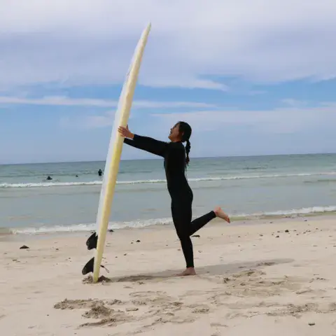 Surfeuse avec sa planche sur la plage