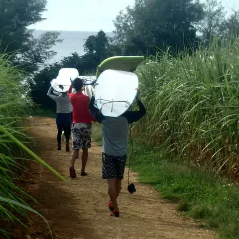 Surfeurs portant leurs planches sur un chemin