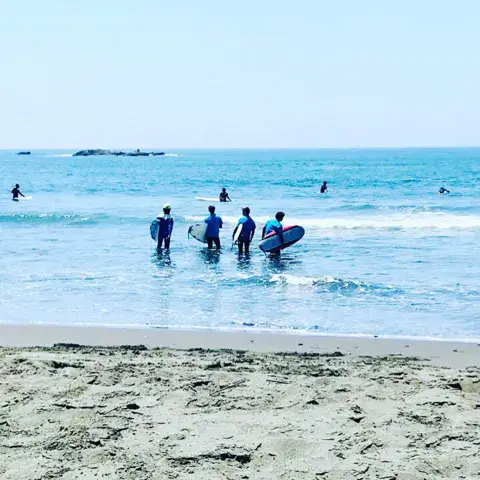 Élèves entrant dans l'eau avec leurs planches