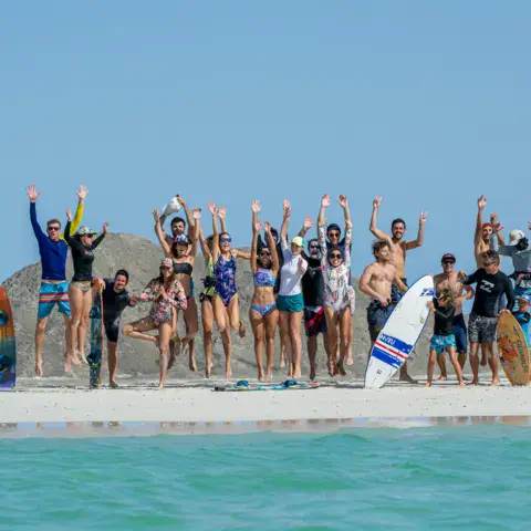 Groupe de riders qui sautent sur la plage avec leurs planches