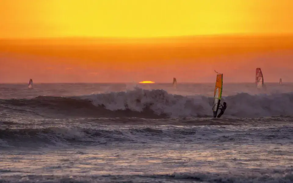 Session de windsurf dans les vagues au coucher du soleil