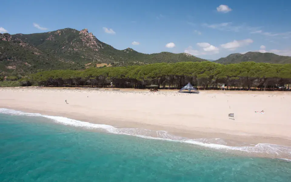 Plage de sable et mer turquoise devant la pinède, vue depuis l'eau