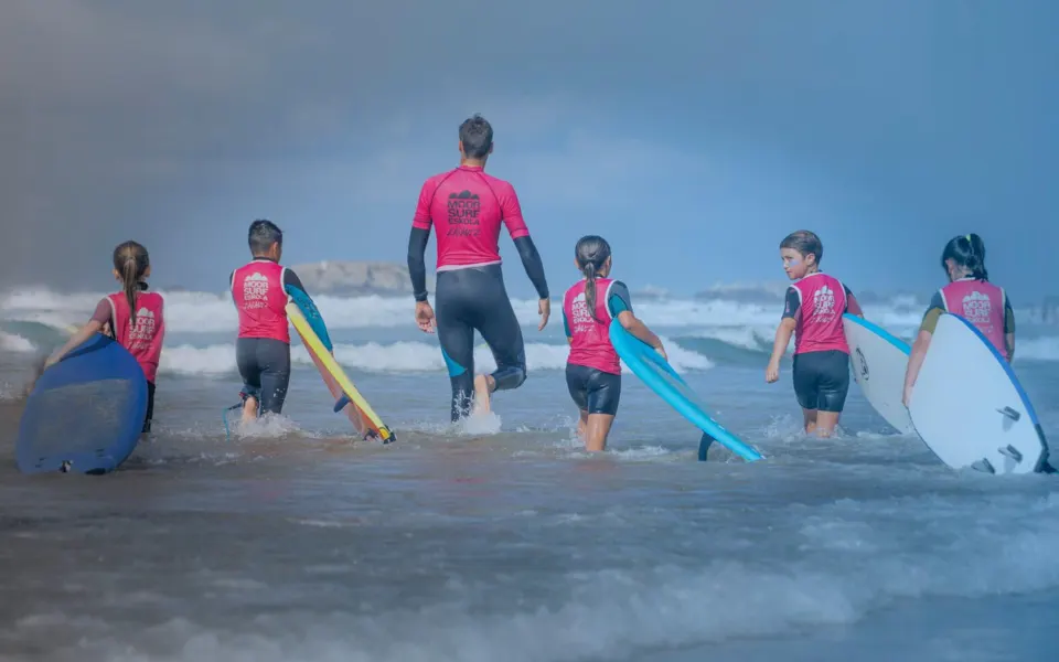 Groupe de surf entrant dans l'eau avec un moniteur