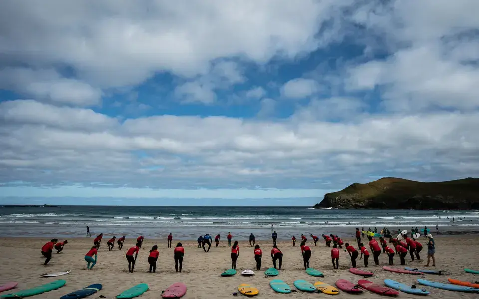 Groupe d'élèves en échauffement sur la plage de Pantín, planches alignées