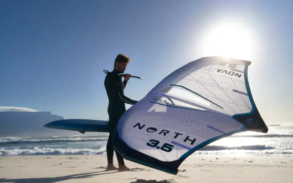 Rider avec une aile de wingfoil sur la plage