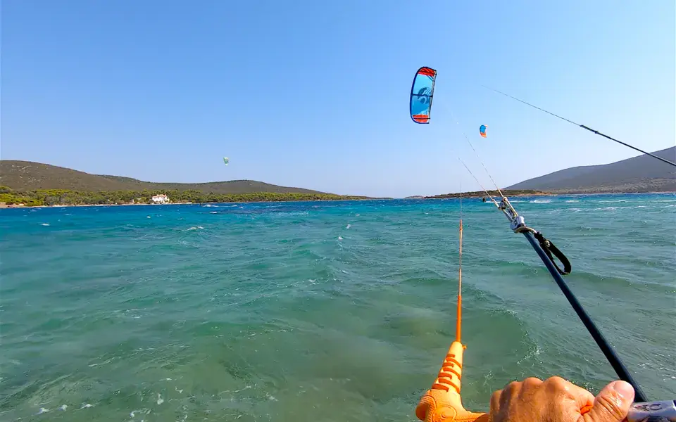 Vue d'un kitesurfeur, barre en main, au-dessus de l'eau