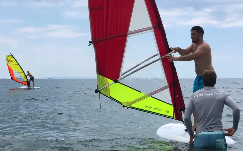 Cours de windsurf avec un instructeur dans l'eau