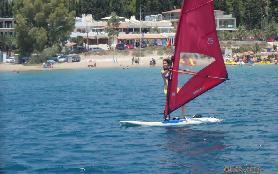 Planche à voile à voile rouge dans la baie