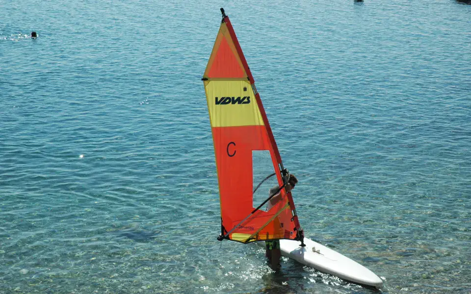 Planche à voile à voile orange dans une eau claire
