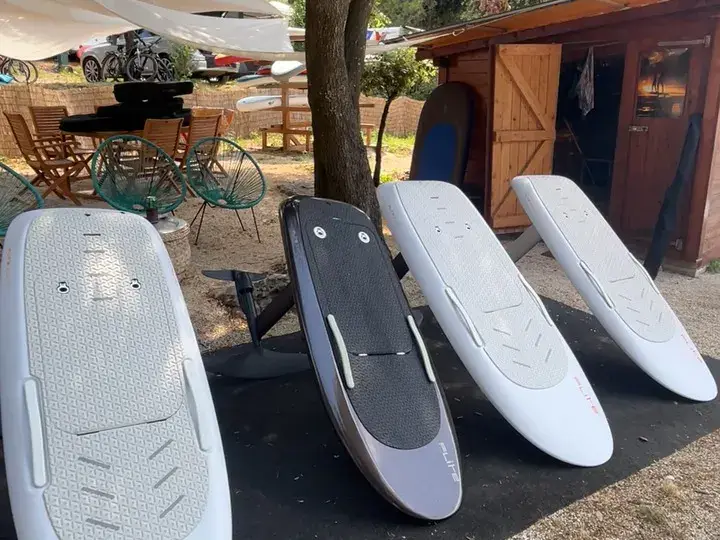 Quatre planches e-foil alignées devant la cabane du centre