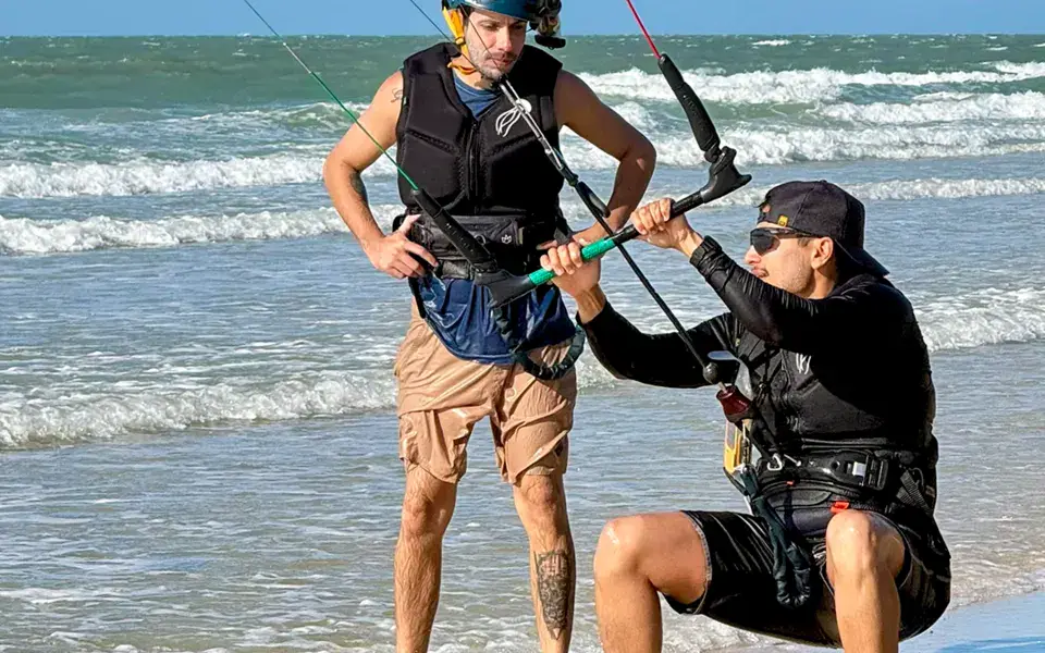 Moniteur et élève avec la barre de kite sur la plage