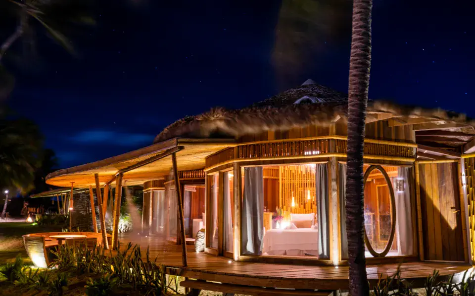Bungalow illuminé de nuit sous les palmiers