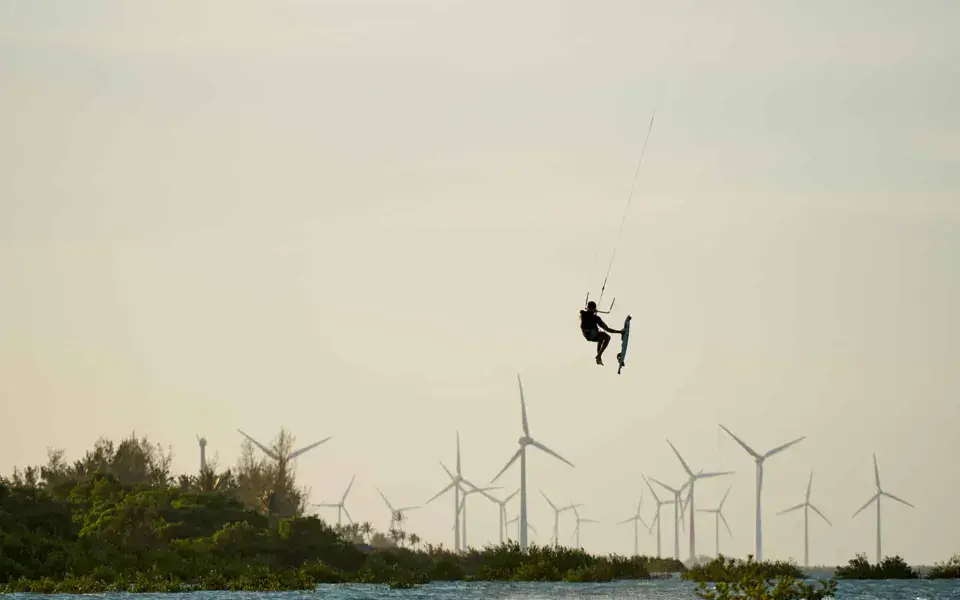Kitesurfeur en saut devant des éoliennes