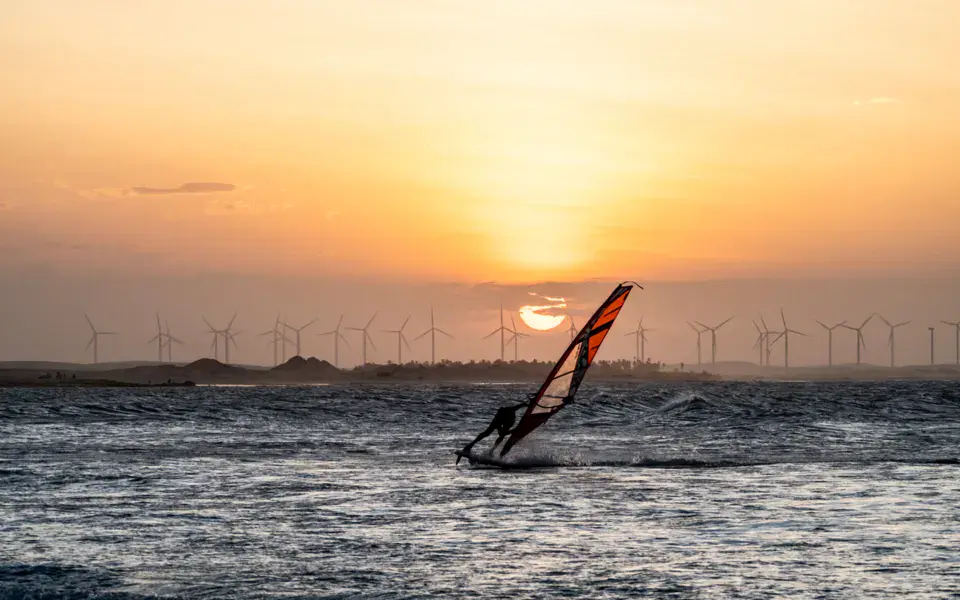 Windsurfeur au coucher du soleil devant des éoliennes
