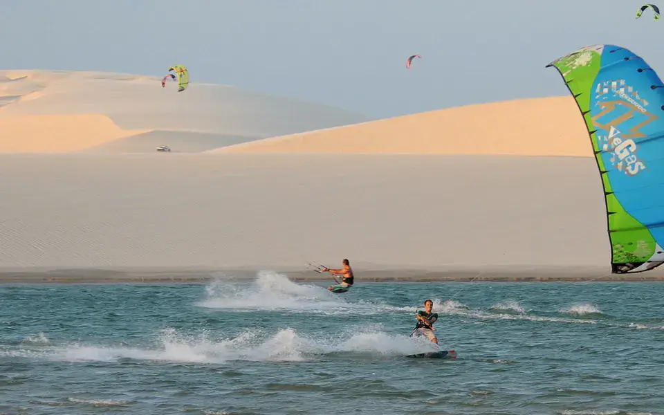 Kitesurfeur sur l'eau devant des dunes