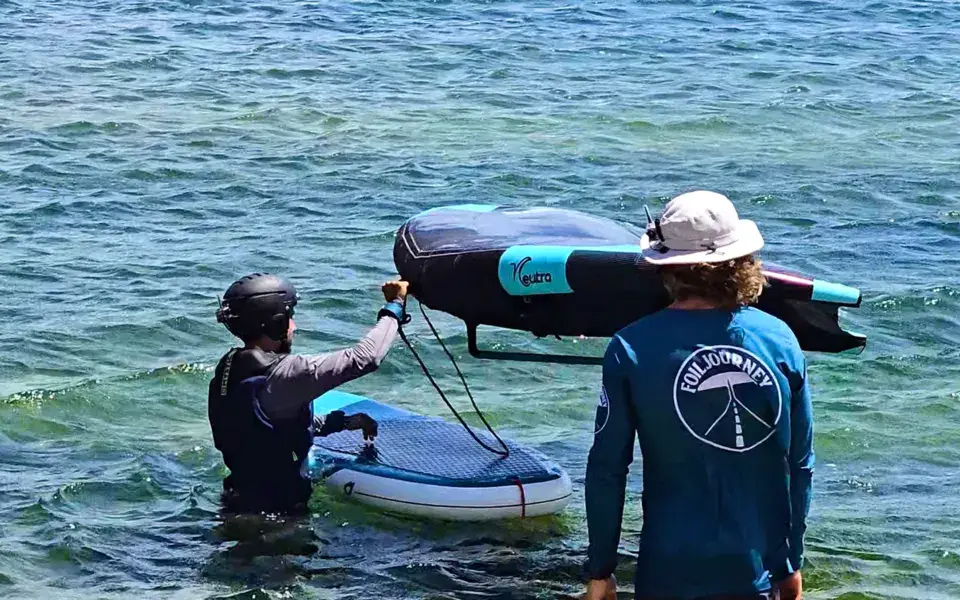 Moniteur et élève avec une aile de wing en eau peu profonde