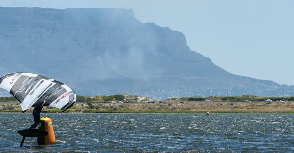 Rider de wingfoil sur le plan d'eau, montagne en arrière-plan