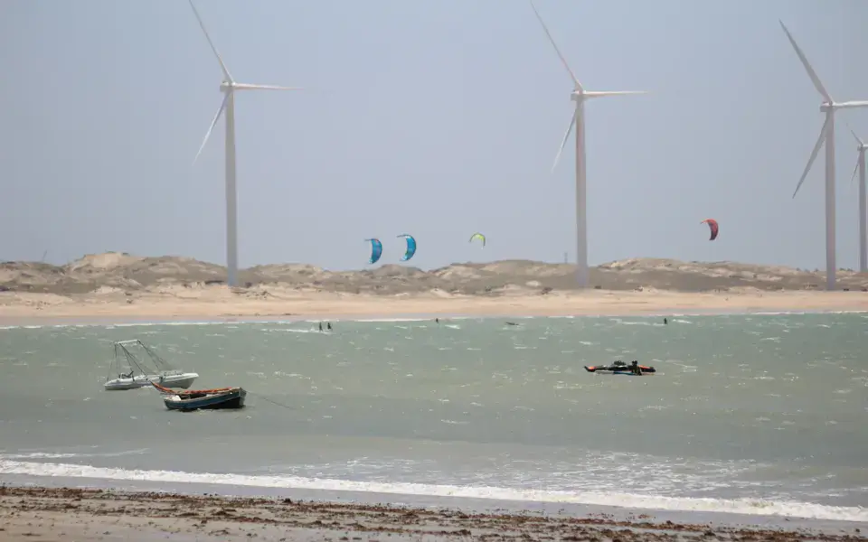 Kites au large d'une plage, éoliennes en arrière-plan
