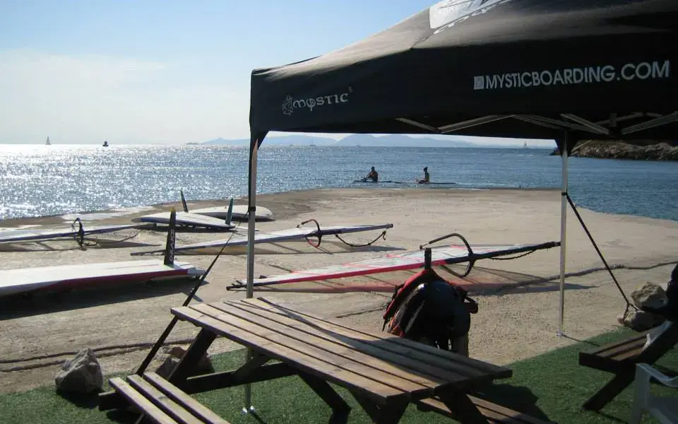 Tonnelle et tables en bord de plage devant le matériel de windsurf