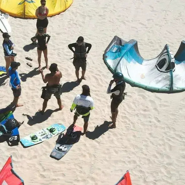 Groupe sur la plage autour d'un kite et de planches