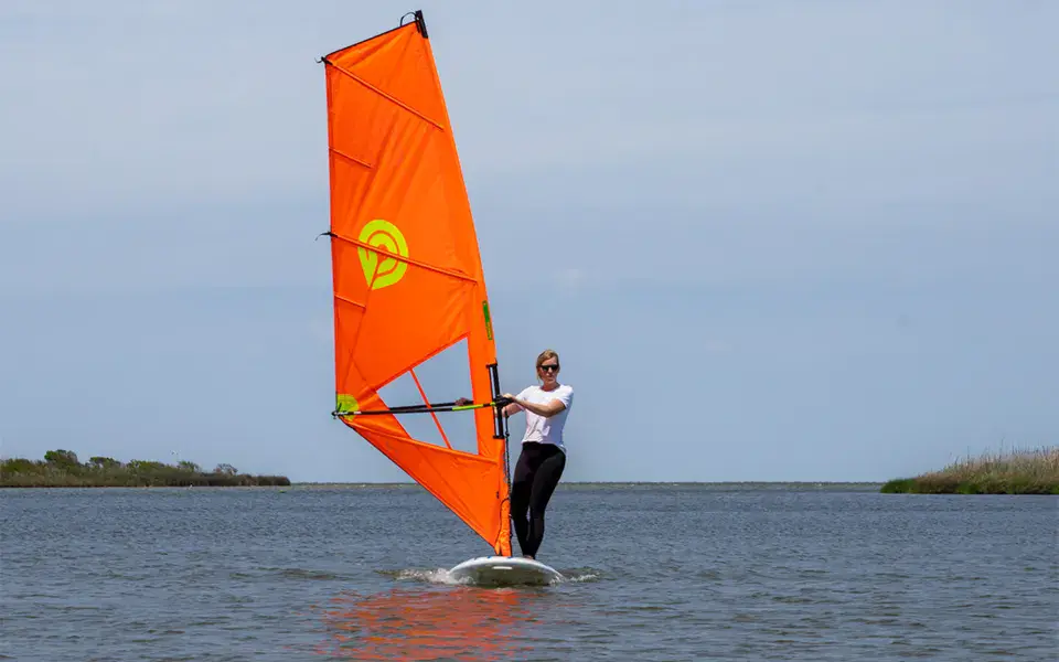 Windsurfeur sur un plan d'eau calme avec une voile orange