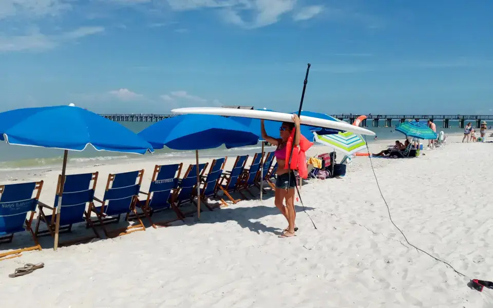 Plage de sable blanc avec parasols et planche de paddle