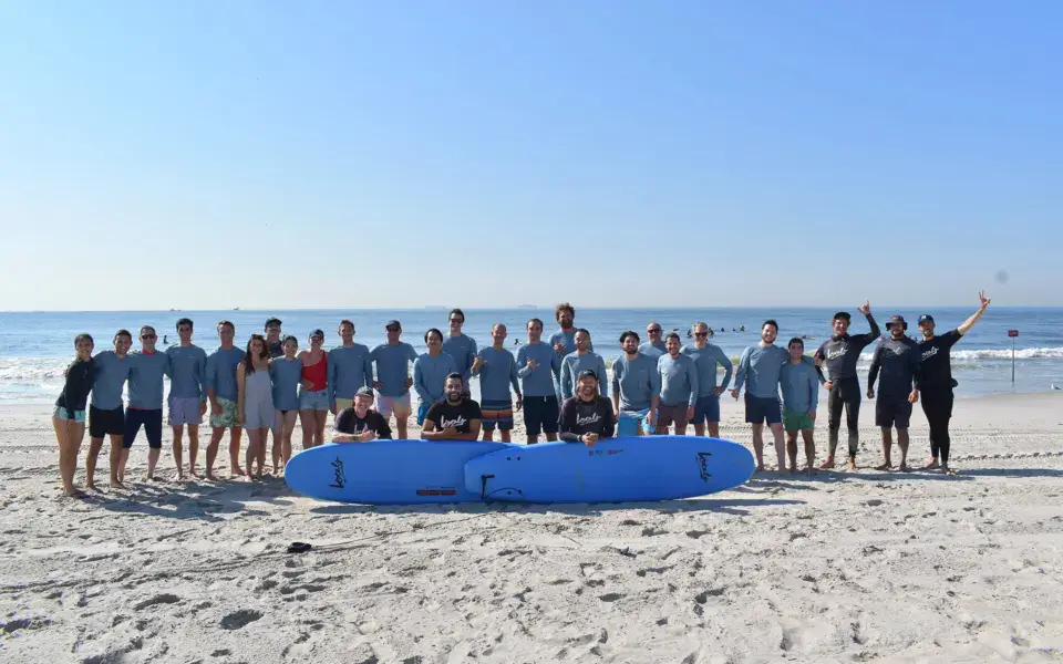 Groupe d'élèves et de moniteurs sur la plage avec les planches