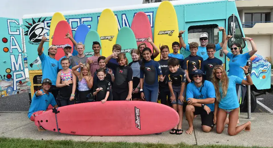 Groupe de stagiaires devant le camion du stage de surf avec leurs planches