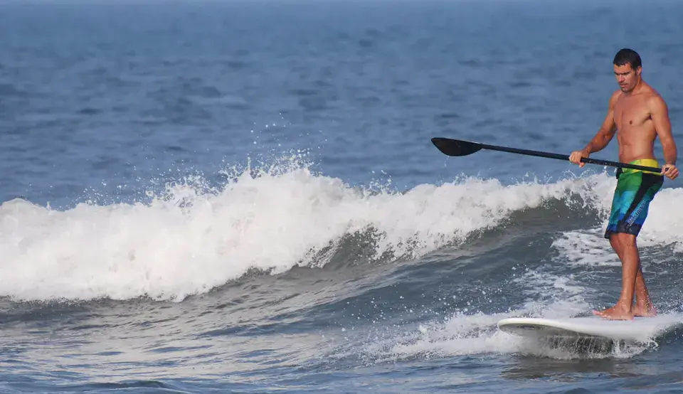 Pagayeur sur une planche de paddle dans une vague