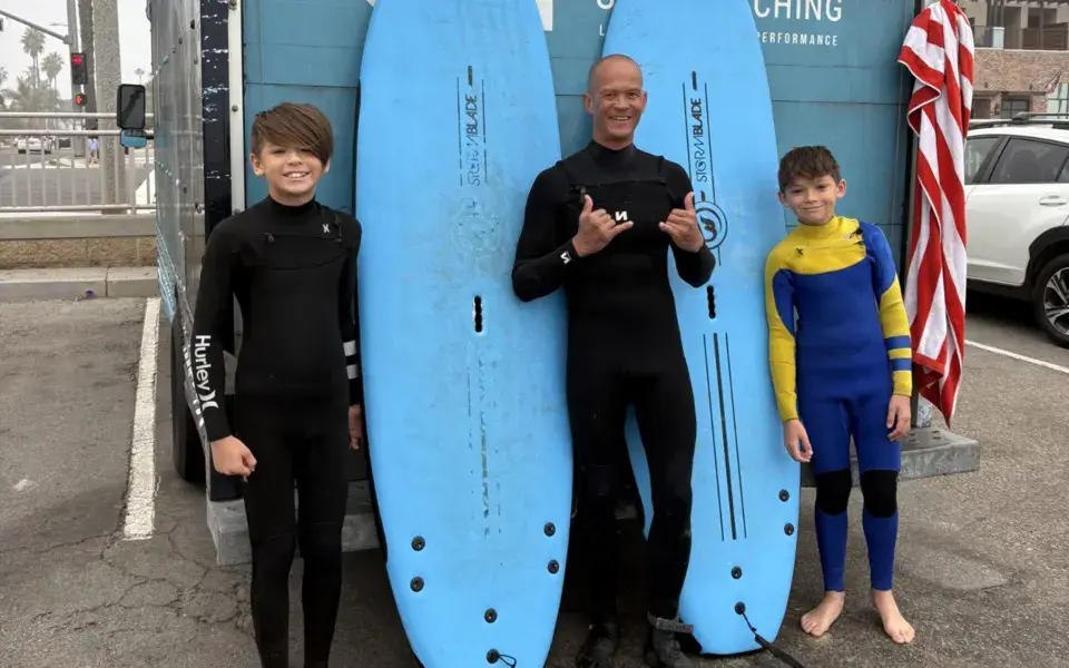 Le coach avec deux élèves devant les planches de l'école