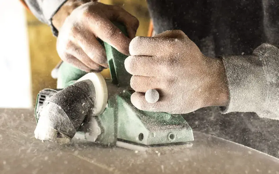 Ponçage d'une planche de surf à la main, à l'atelier