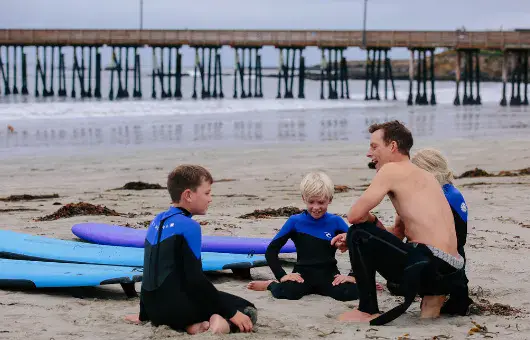 Cours de surf sur la plage, avec la jetée en arrière-plan