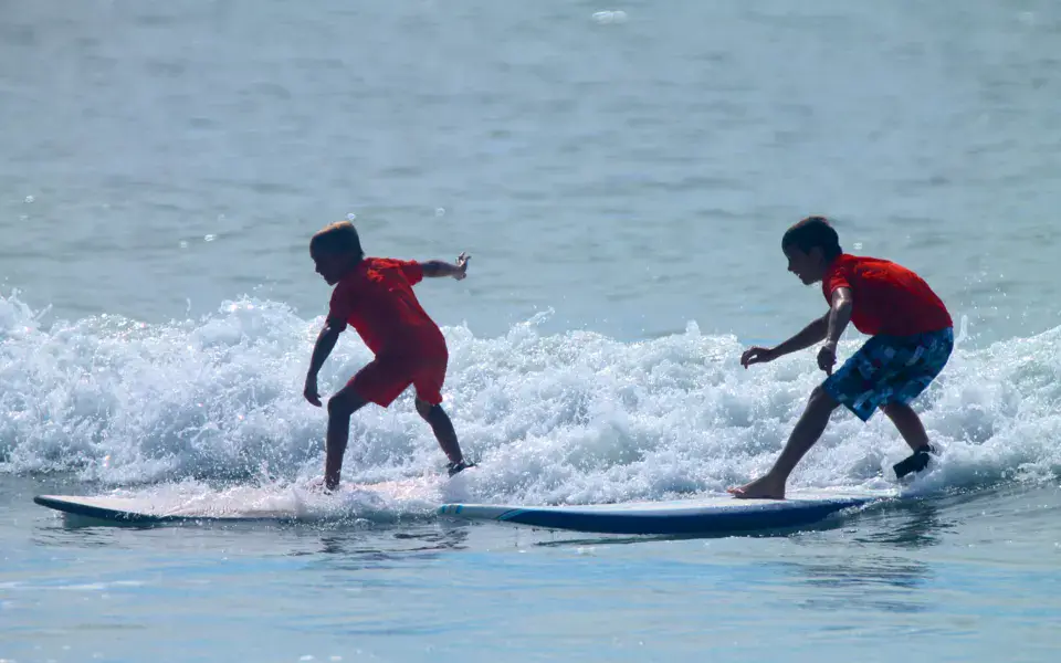 Deux jeunes surfeurs debout sur leur planche dans les vagues