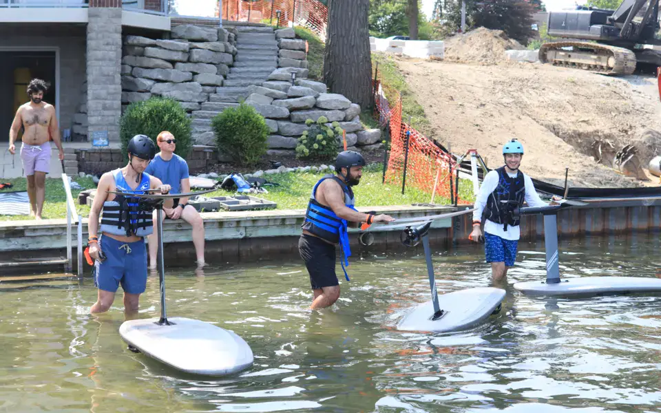 Groupe d'élèves avec leurs planches d'e-foil dans l'eau, au bord d'un ponton