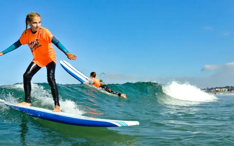 Jeune surfeuse debout sur une vague