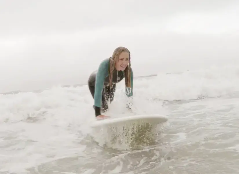 Élève de surf sur une planche dans l'écume