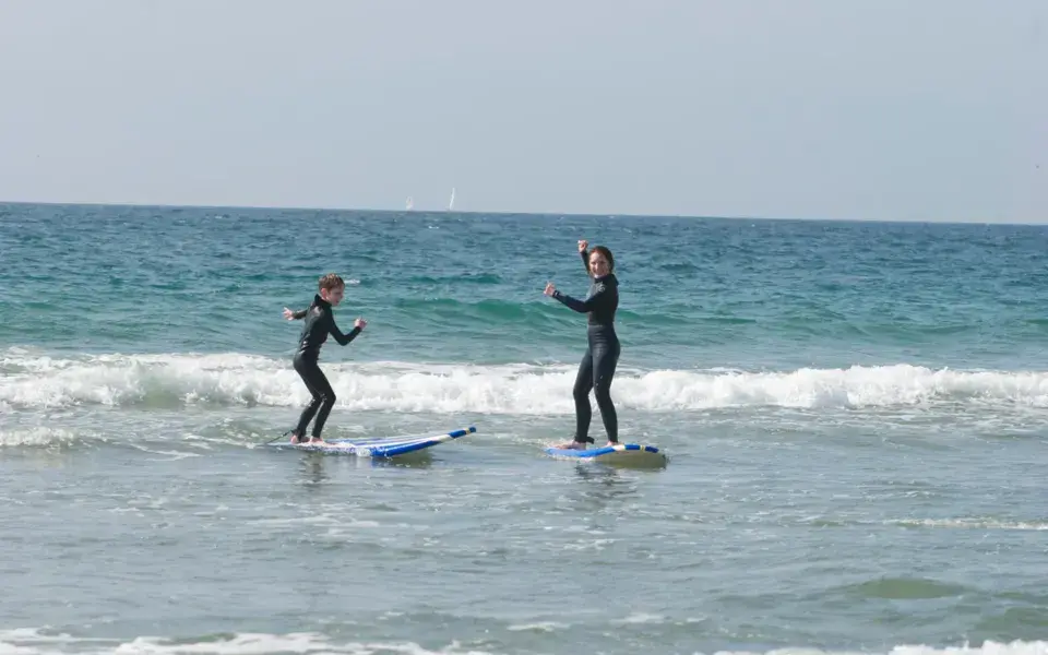 Deux élèves debout sur leur planche dans l'eau peu profonde