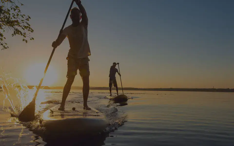 Deux personnes en stand up paddle au coucher du soleil