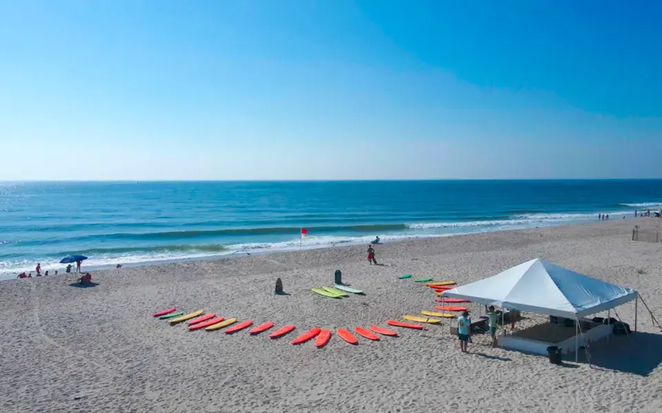 Installation de l'école sur la plage : planches alignées sur le sable et tente